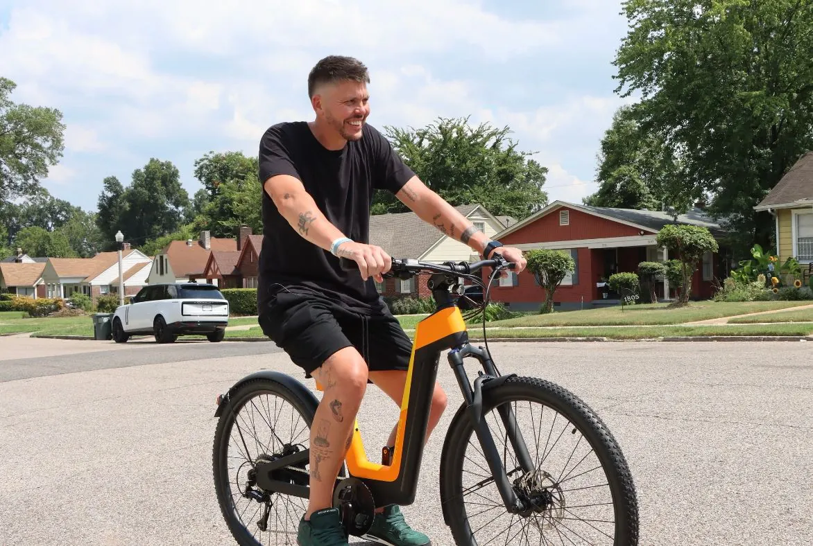 Mike Miller riding an Aivela smart-ring campaign e-bike down a suburban street