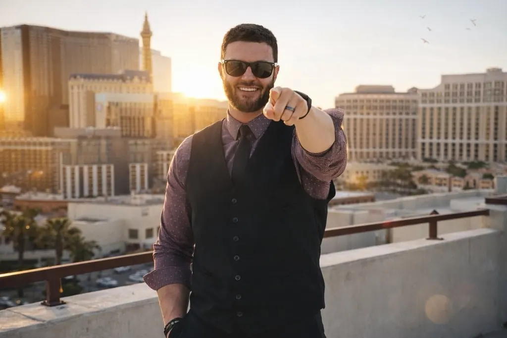 Adam, the DUI Doctor, on a rooftop above the Las Vegas Strip at sunset, in sunglasses, a patterned shirt, black vest and tie, pointing at the camera