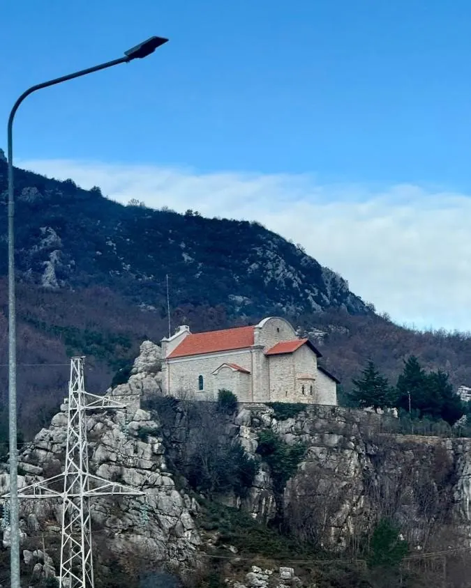 Figure 25 · the stone Church of the Rubik Monastery on a rocky elevation in northern Albania, red roof against the hillside