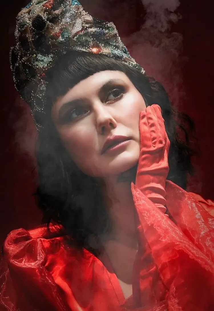 A model in red couture with an ornate jeweled headpiece, photographed through haze